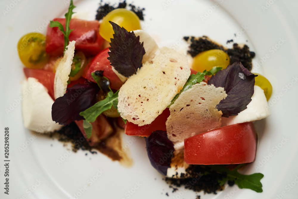 Vegetarian food with marinated tomatoes, arugula, mozzarella cheese, balsamic jelly, olive oil. Delicious healthy food concept, close-up Vegetarian food with marinated tomatoes, arugula, mozzarella cheese, balsamic jelly, olive oil. Delicious healthy food concept, close-up