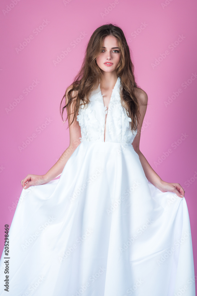 Fashion model or princess at prom. Wedding fashion and beauty salon. Bride girl at wedding ceremony. Sexy girl in white dress with stylish hair. Woman on pink background in summer dress Fashion model or princess at prom. Wedding fashion and beauty salon. Bride girl at wedding ceremony. Sexy girl in white dress with stylish hair. Woman on pink background in summer dress