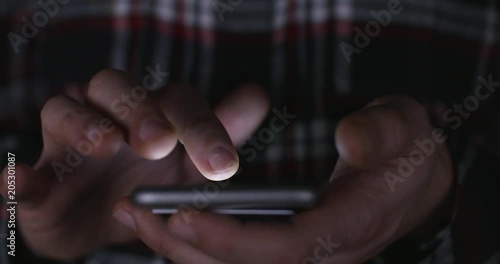 Online gambling: a close up of a man placing a bet via online gambling on his phone late at night and crossing his fingers for good luck. 4k Slow motion.