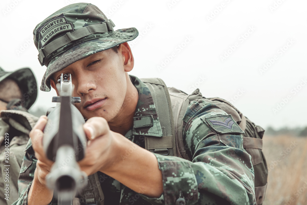 Soldier aiming his weapon. Standing up aiming their assault rifle down range. Portrait close up shot. Digital green camo. Soldier aiming his weapon. Standing up aiming their assault rifle down range. Portrait close up shot. Digital green camo.