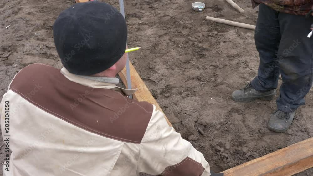 Two workmen talking and making wooden frame on ground on construction Two workmen talking and making wooden frame on ground on construction