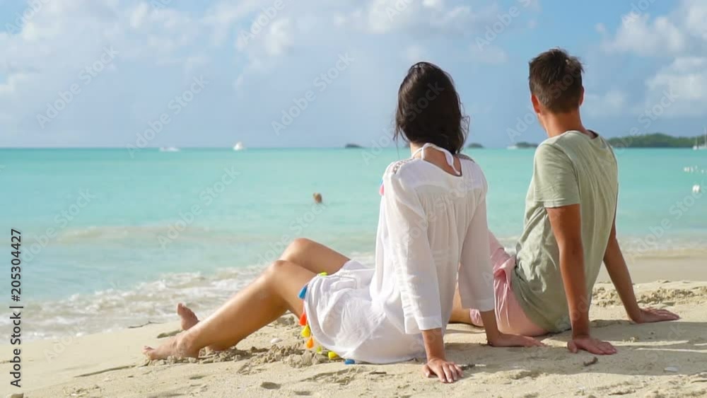 Young couple on white beach during summer vacation. Happy lovers enjoy their honeymoon at exotic island Young couple on white beach during summer vacation. Happy lovers enjoy their honeymoon at exotic island