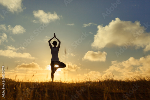 Fototapeta Naklejka Na Ścianę i Meble -  Woman doing yoga balancing exercise outdoors. Body health, active lifestyle concept. 