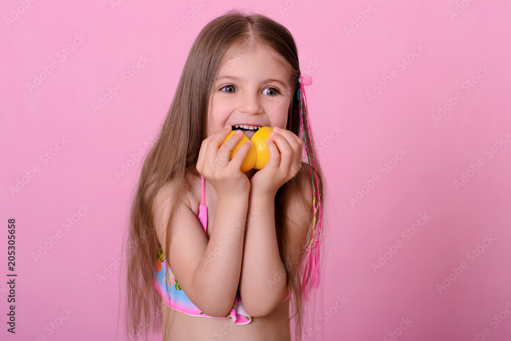 Caucasian beautiful little girl with fresh yellow lemons on a pink background Caucasian beautiful little girl with fresh yellow lemons on a pink background
