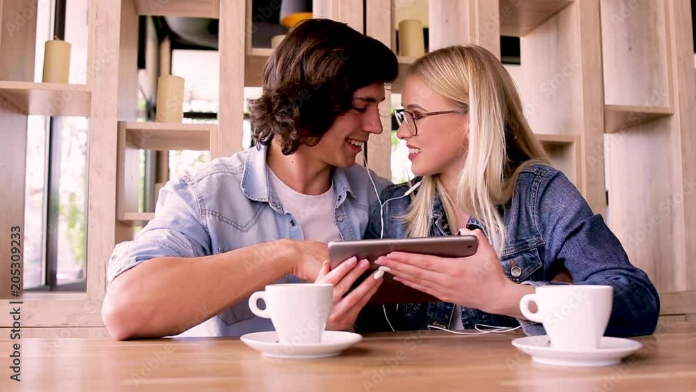 Young Charming Couple Using Tablet While Sitting Together And Drinking Coffee Young Charming Couple Using Tablet While Sitting Together And Drinking Coffee
