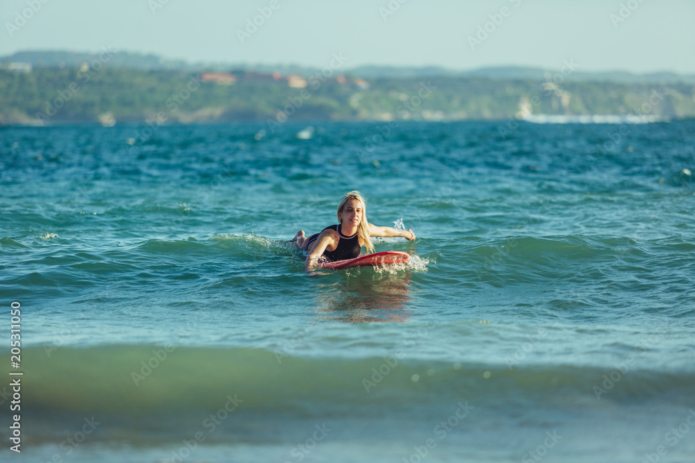 beautiful sportswoman swimming on surfboard in water