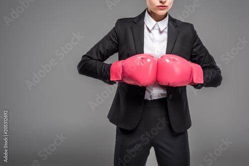 cropped view of strong businesswoman posing in boxing gloves, isolated on grey © LIGHTFIELD STUDIOS