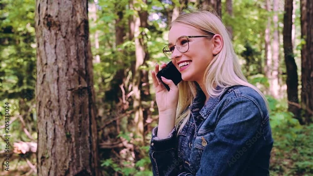 Young Cheerful Blond Woman Talking On Phone While Standing In Forest Young Cheerful Blond Woman Talking On Phone While Standing In Forest