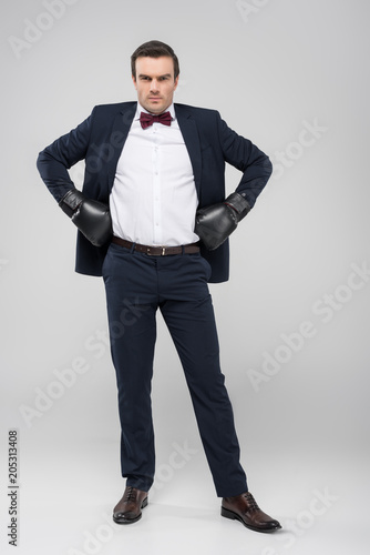 handsome groom posing in tuxedo and boxing gloves, isolated on grey © LIGHTFIELD STUDIOS