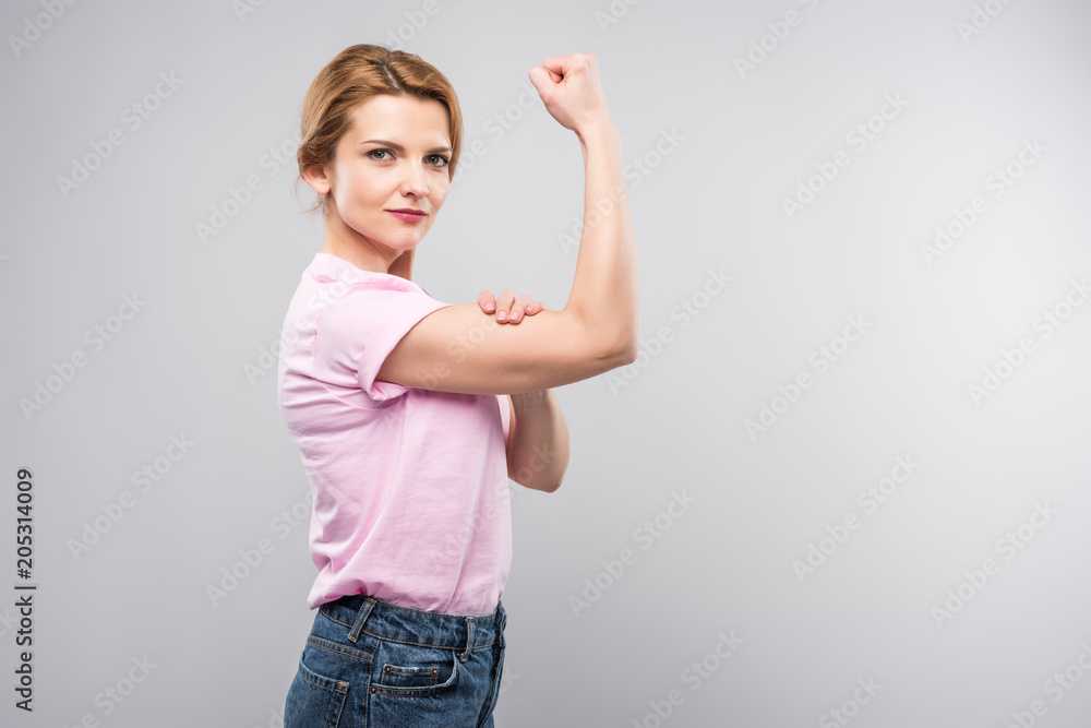 feminist woman in pink t-shirt showing muscles, isolated on grey feminist woman in pink t-shirt showing muscles, isolated on grey