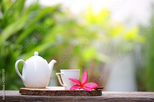 White kettle and cup with plumaria flower at outdoor photo