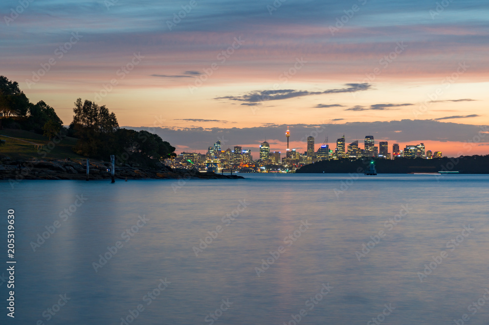 Distant silhouette of Sydney cityscape at dusk, on sunset