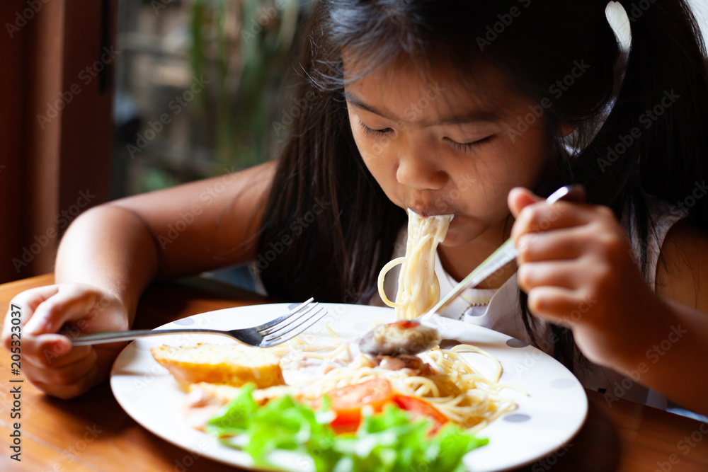 Asian child girl eating delicious Spaghetti Carbonara in the restaurant Asian child girl eating delicious Spaghetti Carbonara in the restaurant