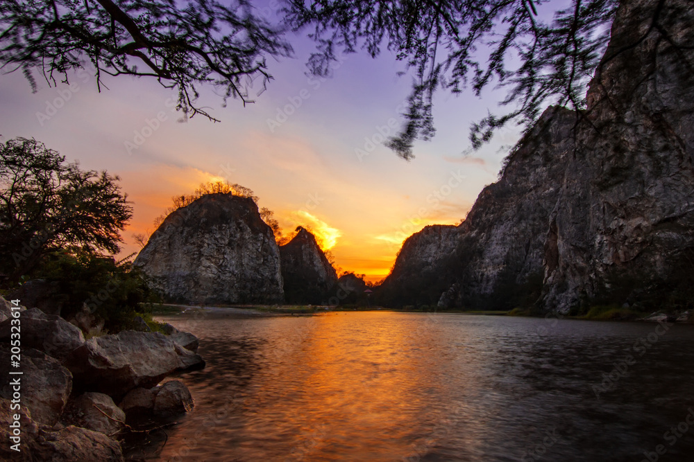 Twilight evening sunset cloudy sky reflect color on water lake with high rock cliff mountain background landscape Twilight evening sunset cloudy sky reflect color on water lake with high rock cliff mountain background landscape