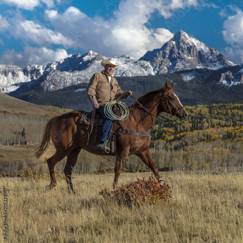 Cowboy rides horse across historic Last Dollar Ranch on Hastings Mesa, SW Colorado, San Juan Mountains