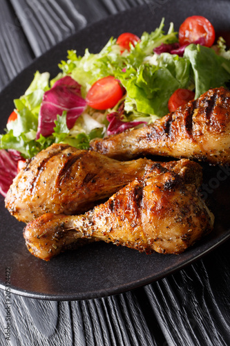 Crispy grilled chicken legs and fresh vegetable salad close-up. vertical
