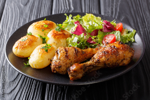 Hot grilled chicken legs with potatoes and fresh salad close-up. horizontal