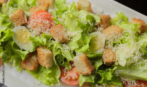 Caesar salad on a white plate and a glass background