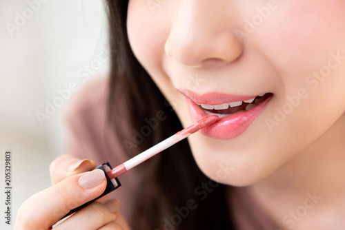 Young beautiful woman applying lipstick cream to her mouth