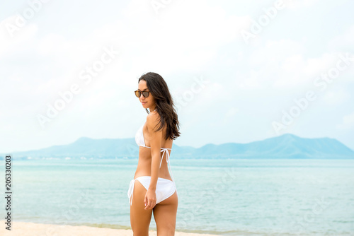 Beautiful woman in white bikini swimsuit at the beach in summer