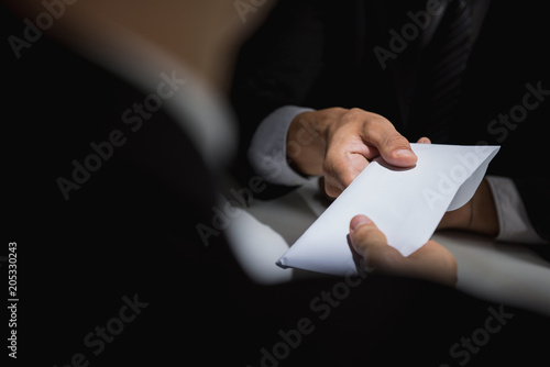 Businessman giving bribe money in the envelope to partner photo