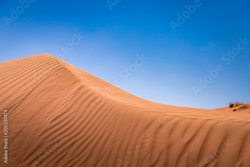 Shadows and ripples on a sand dune ridge, in the desert by Al Wasil, Oman.