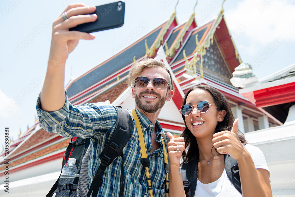 Obraz premium Tourist couple taking selfie at Thai temple on vacations in Thailand