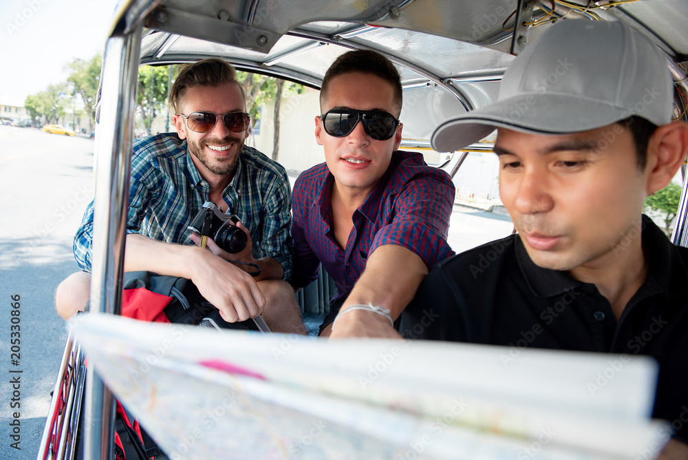 Fototapeta premium Tourists talking with driver asking for location while traveling by local Tuk Tuk taxi in Bangkok Thailand