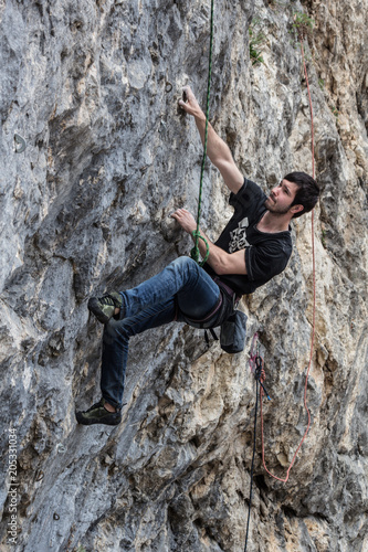 A climber in climbing gear scrambles up the rock