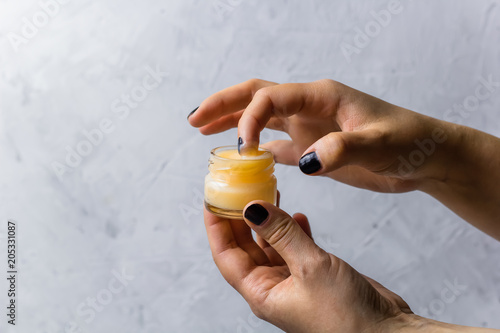 female hands holding cosmetic product in a glass jar