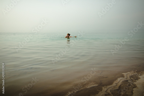 Funny girl swims in water of Dead Sea in Jordan and fog © keleny