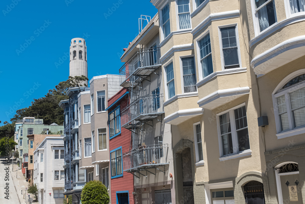 San Francisco, typical colorful houses in Telegraph Hill, sloping street, with the Coit tower in background

