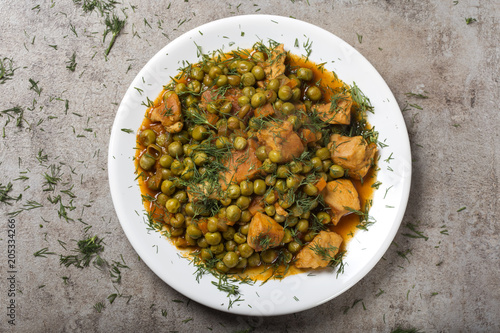 Chiken stew with peas, carrot and tomato sauce on plate with chopped dill photo