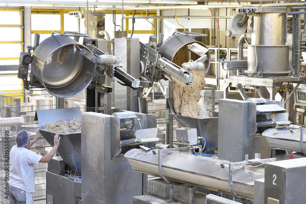 Arbeiter bedient Knetmaschinen in einer Großbäckerei - industrielle Herstellung am Fliessband von Brot in der Lebensmittelindustrie // kneading machines in a large bakery - food industry