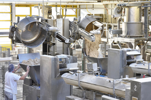 Arbeiter bedient Knetmaschinen in einer Großbäckerei - industrielle Herstellung am Fliessband von Brot in der Lebensmittelindustrie // kneading machines in a large bakery - food industry