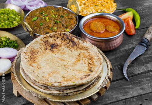 Indian Cuisine Chapati Also Called Roti, Flatbread, Chapathi or Chapatti Served With Sev Tamatar, Gatta Curry, Raita, Papad or Onion on Wooden Background