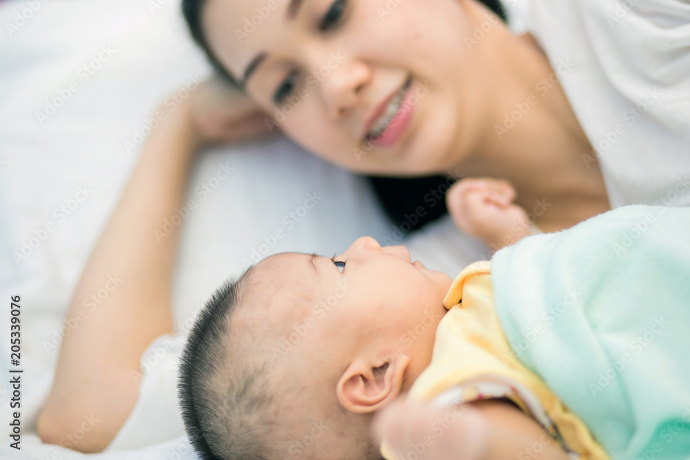 Happy young mom and baby lying on the bed Happy young mom and baby lying on the bed