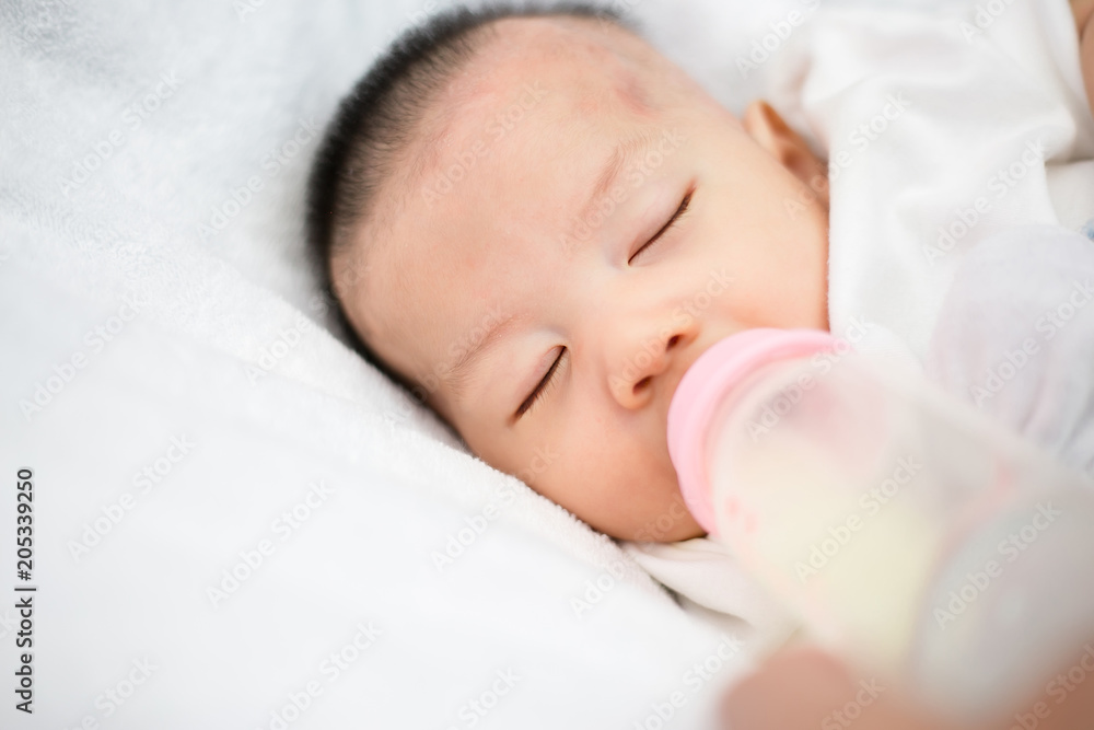 beautiful mother feeding baby boy with a milk bottle at home beautiful mother feeding baby boy with a milk bottle at home
