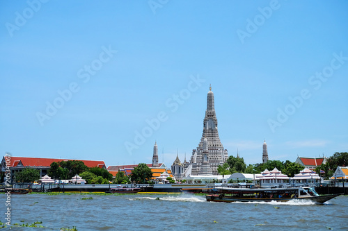 Wat Arun Temple is a buddhist temple in Bangkok, Thailand. Beautiful view of the temple with river and blue sky © panwa