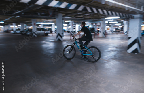 bike rider rides on an underground parking lot. A cyclist rides in an underground parking lot