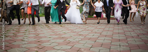 Tela Newlyweds and guests of the wedding walking along the park together