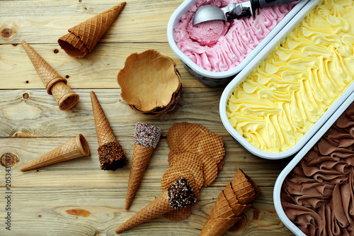 gelato fatto in casa vari gusti fragole vaniglia ciccolato in vaschette di metallo coni e cialde photo