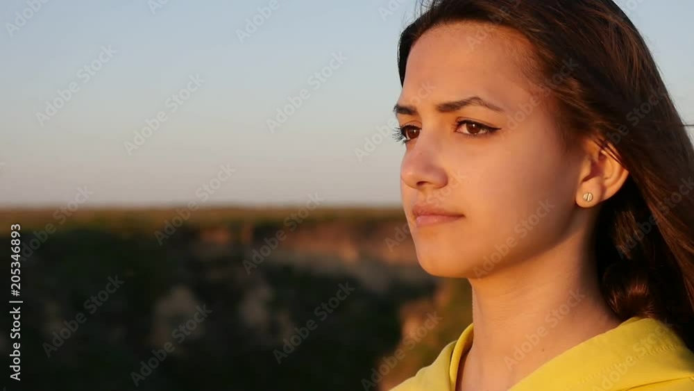Profile of a romantic and stylish girl with long loose hair standing on the hilly Black Sea coast at sunset in summer in slow motion Profile of a romantic and stylish girl with long loose hair standing on the hilly Black Sea coast at sunset in summer in slow motion
