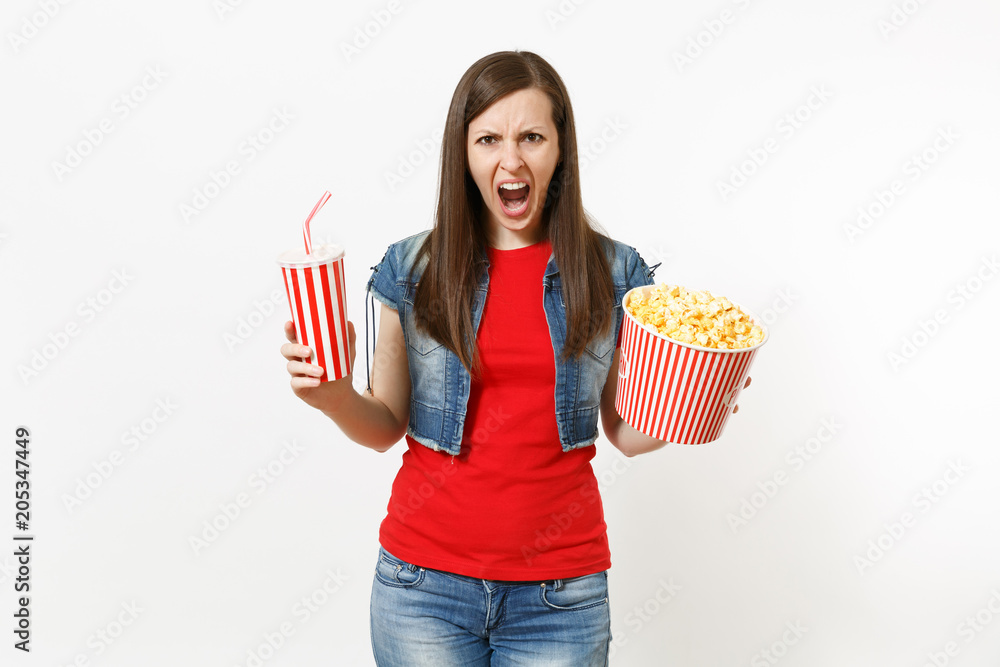 Portrait of irritated scared woman in casual clothes screaming watching movie film, holding bucket of popcorn and plastic cup of soda or cola isolated on white background. Emotions in cinema concept. Portrait of irritated scared woman in casual clothes screaming watching movie film, holding bucket of popcorn and plastic cup of soda or cola isolated on white background. Emotions in cinema concept.