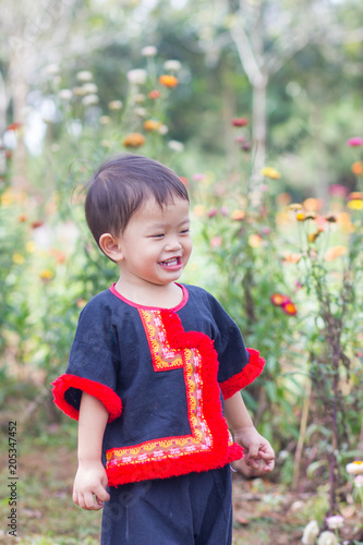 The asian boy is looking at the red flowers in summer