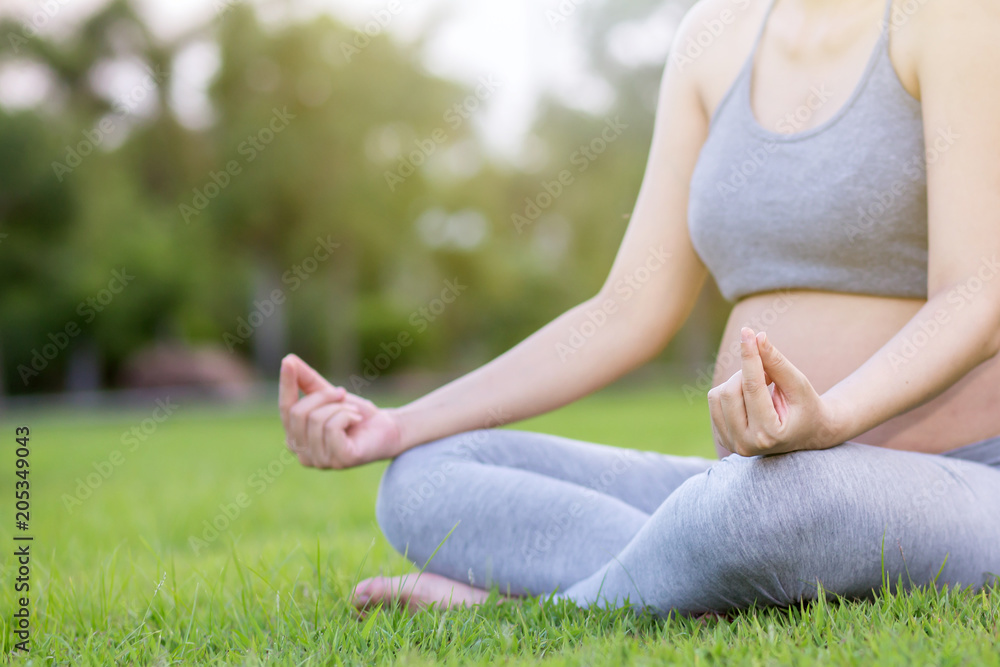 Healthy pregnant woman doing yoga in nature outdoors. Close up