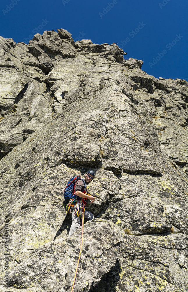 Leading a pitch through a climber in the mountains on a rocky rib. Leading a pitch through a climber in the mountains on a rocky rib.