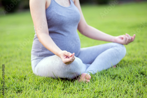 Healthy pregnant woman doing yoga in nature outdoors. Close up