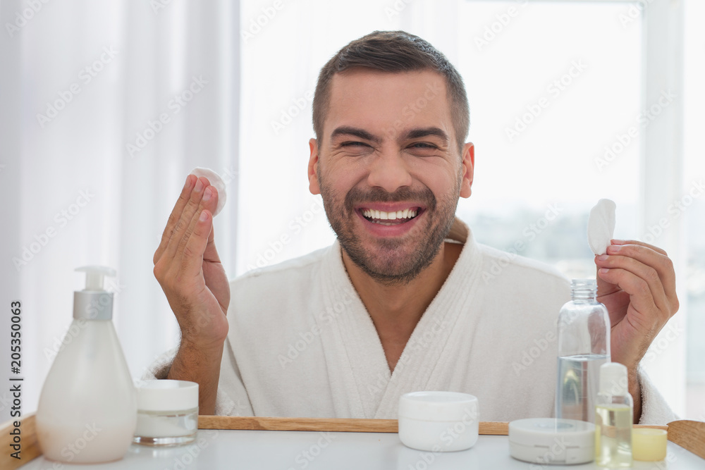 My face. Happy cheerful man looking into the mirror while holding cotton pads in his hands My face. Happy cheerful man looking into the mirror while holding cotton pads in his hands
