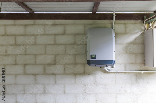Solar power inverter mounted on brick wall inside garage